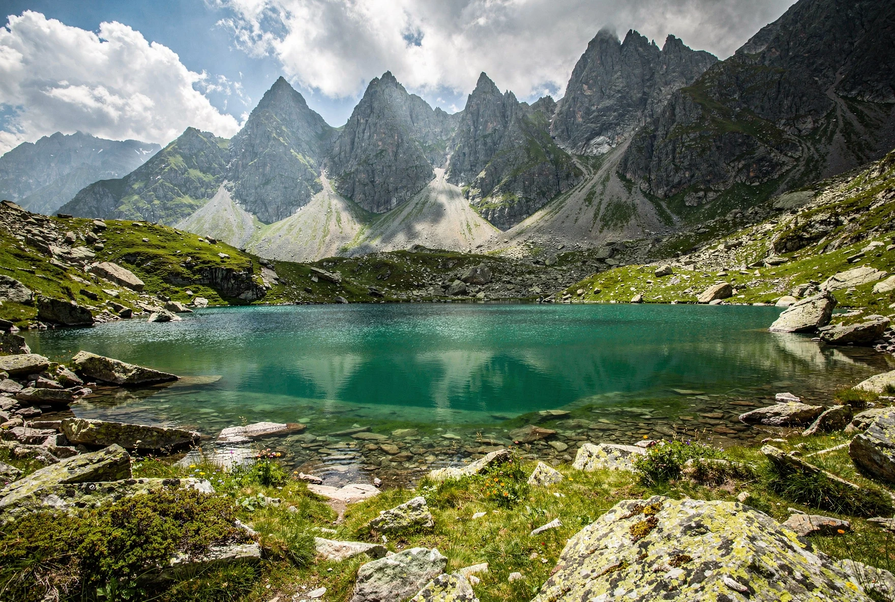 Turquoise alpine lake surrounded by rocky terrain with jagged mountain peaks reflected in the water, Abudelauri Lakes, Georgia