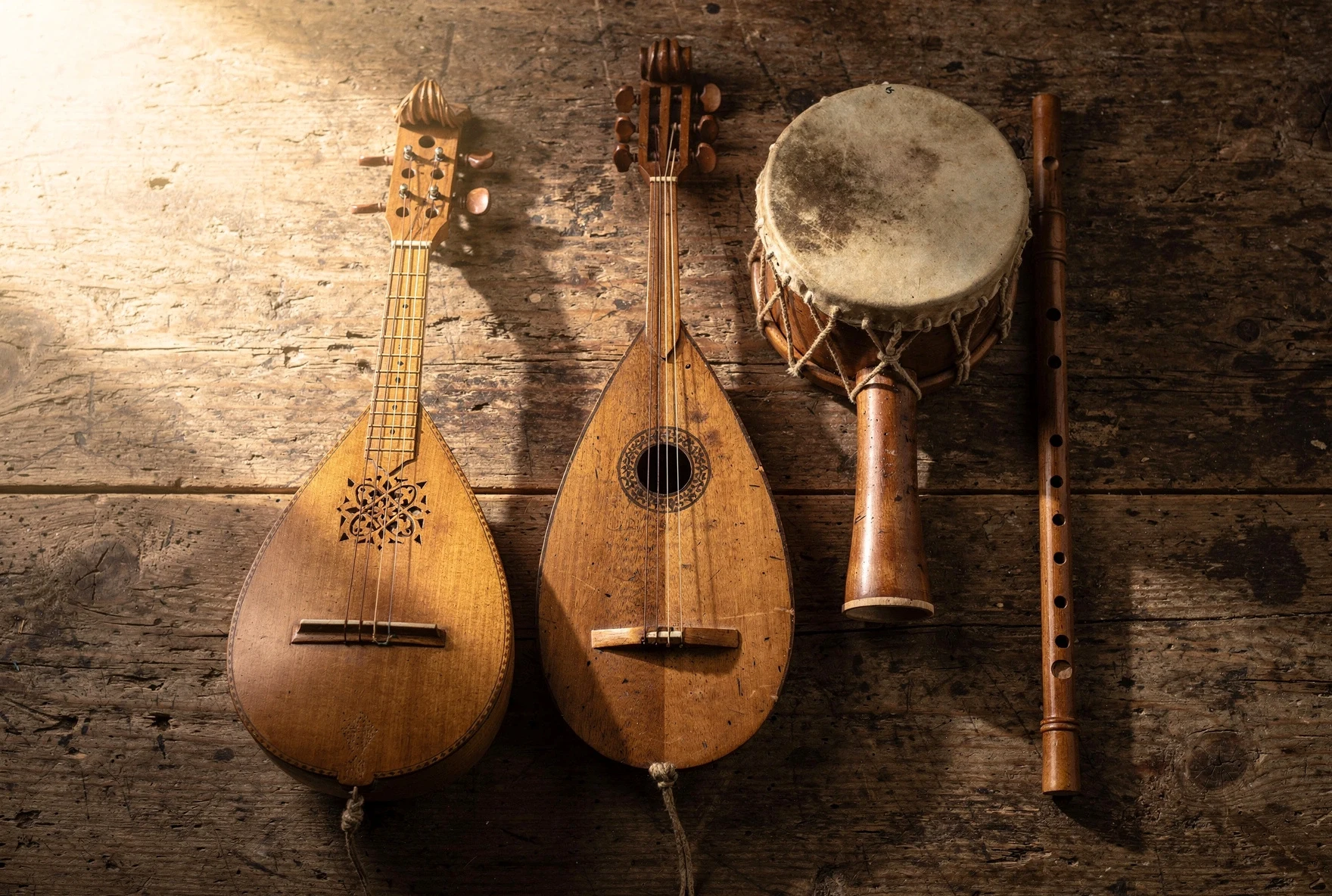 Traditional Georgian musical instruments including panduri, chonguri, doli drum, and salamuri flute on a rustic wooden table