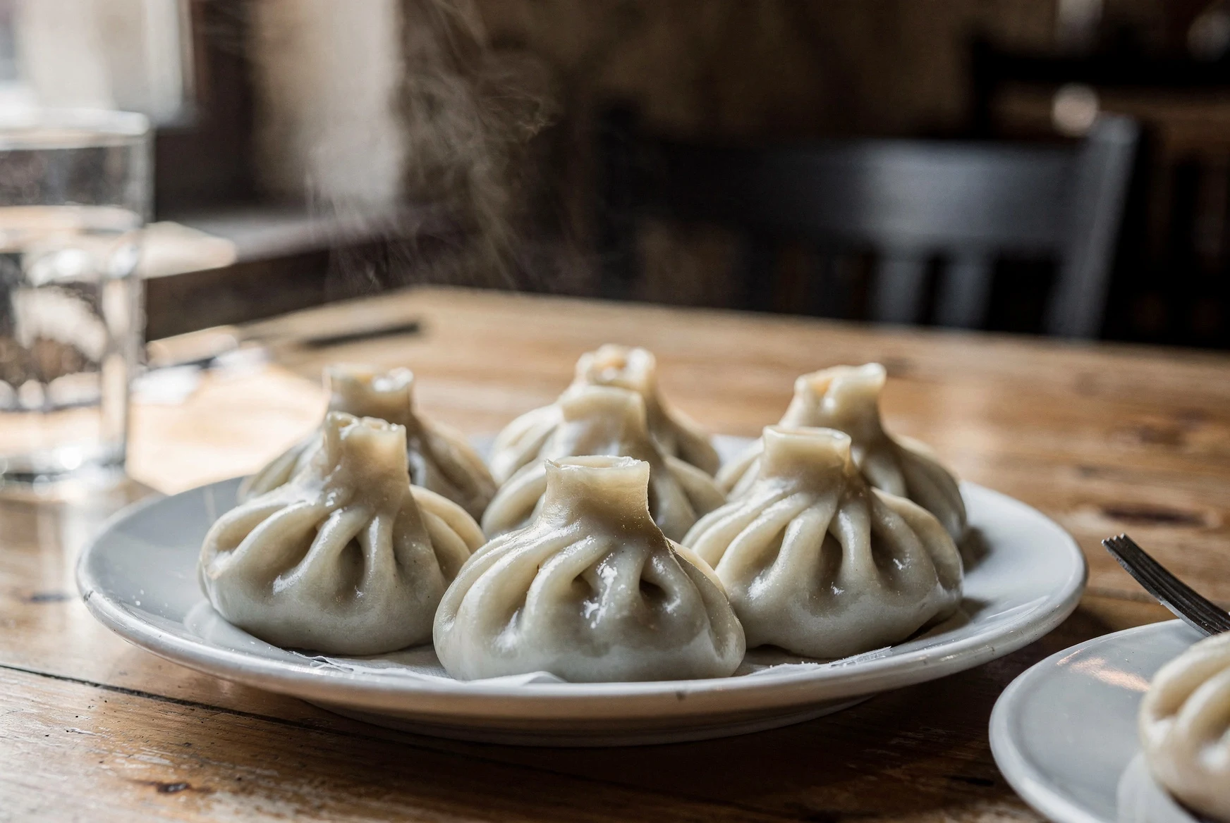 Plate of steaming Georgian khinkali dumplings on a rustic restaurant table