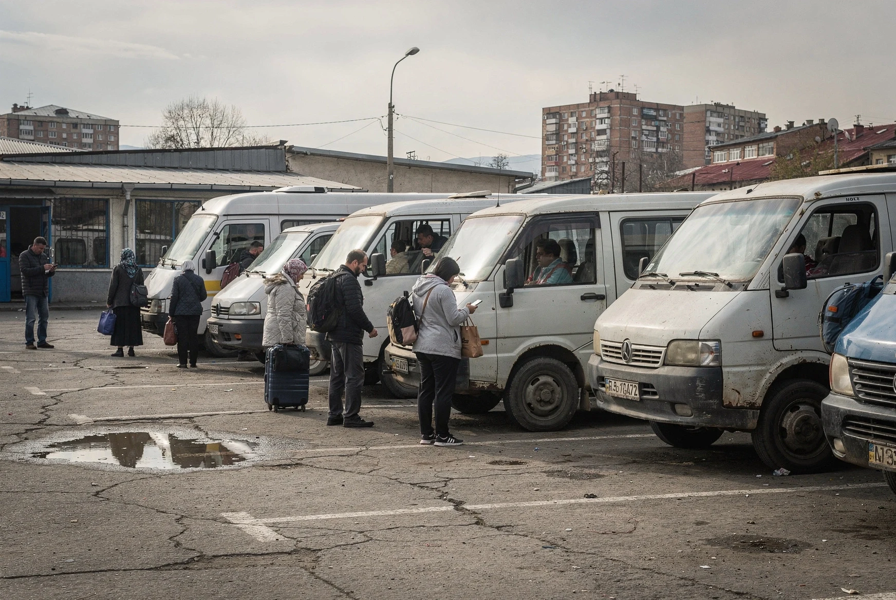 Busy Georgian transport yard with minibuses lined up for departure and travelers boarding
