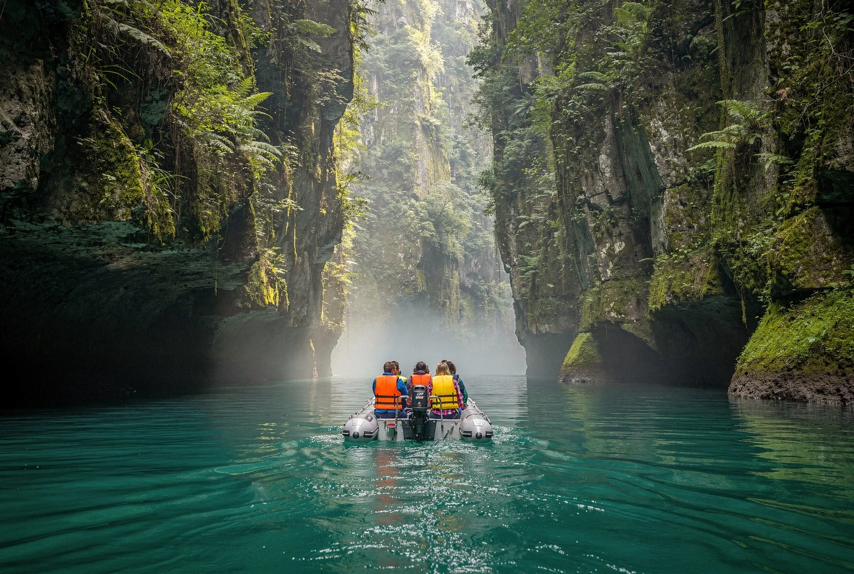 Inflatable boat gliding through the narrow turquoise waters of Martvili Canyon between towering limestone walls