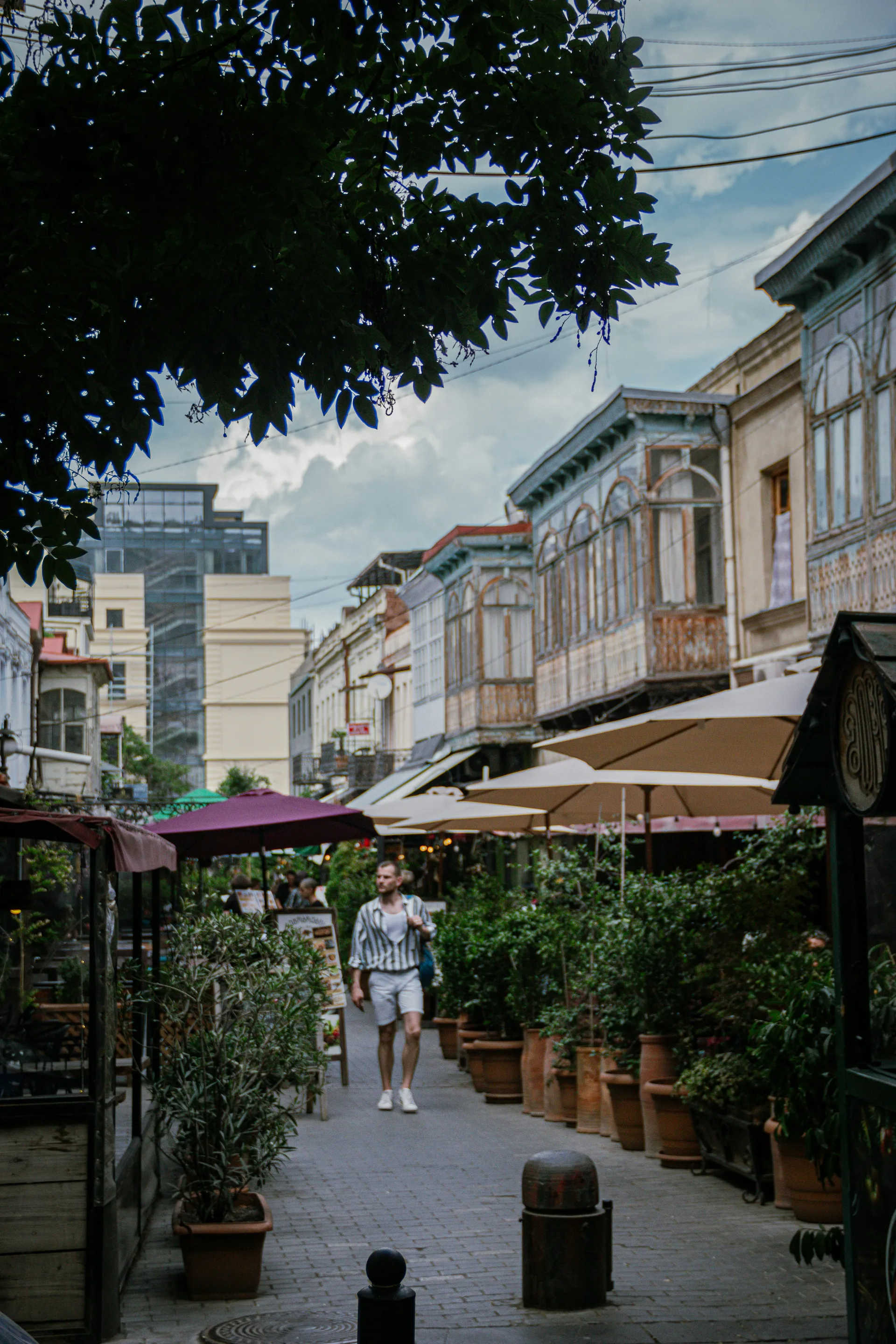A peaceful cobblestone street in Tbilisi lined with cafes and traditional wooden balconies