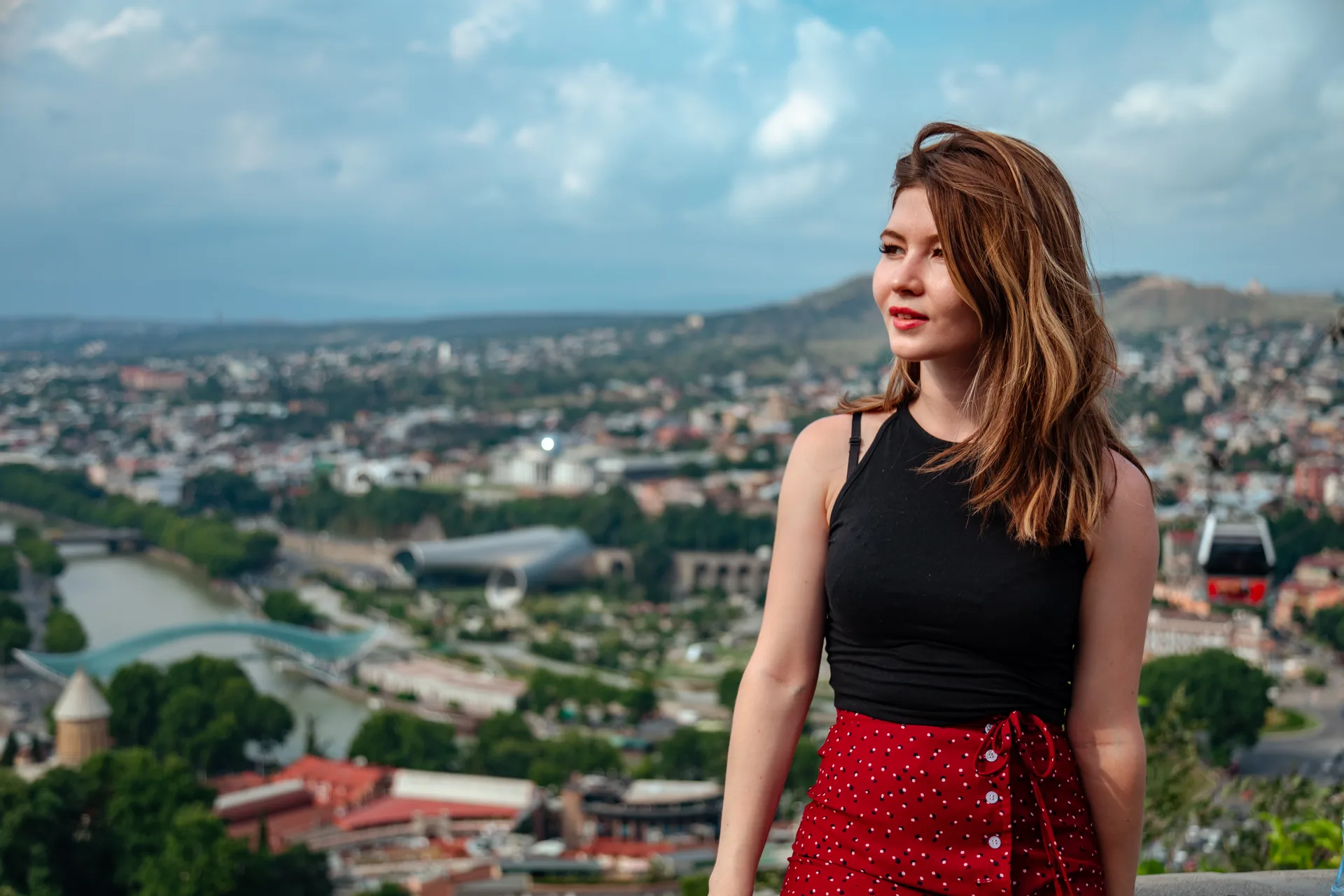 Solo traveler at a viewpoint overlooking Tbilisi with the Bridge of Peace and Kura River