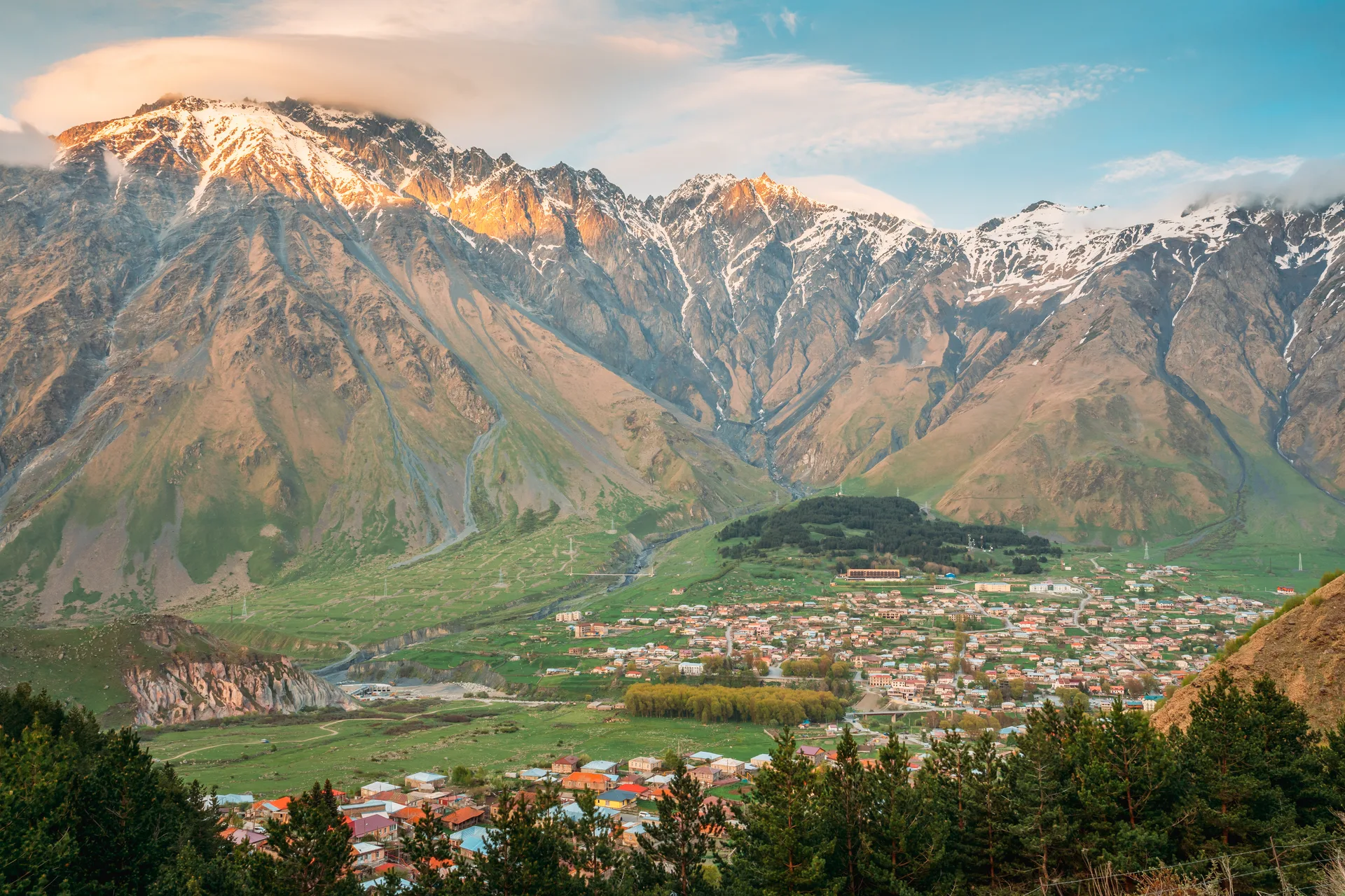 Sunset over the village of Stepantsminda with snow-capped Caucasus peaks