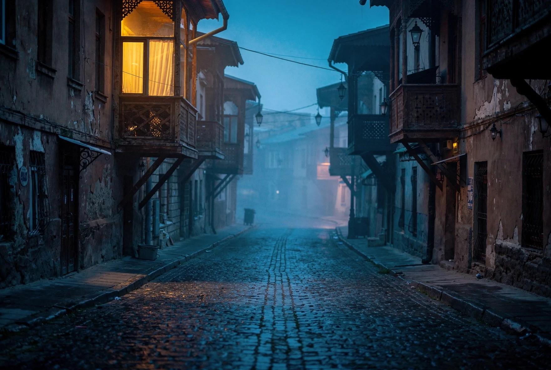 Atmospheric cobblestone street in Tbilisi's Old Town at blue hour with traditional wooden balconies