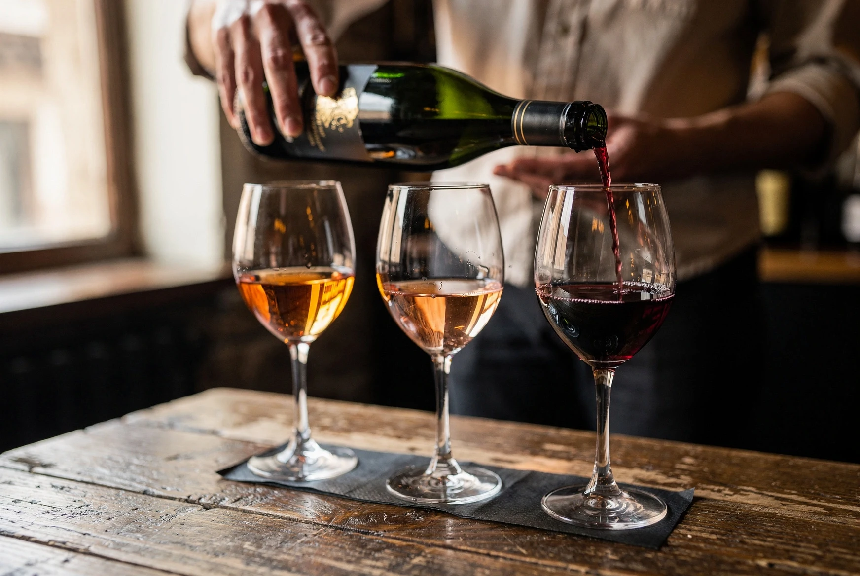 Close-up of a Georgian wine tasting flight with amber, rosé and red wines on a wooden table