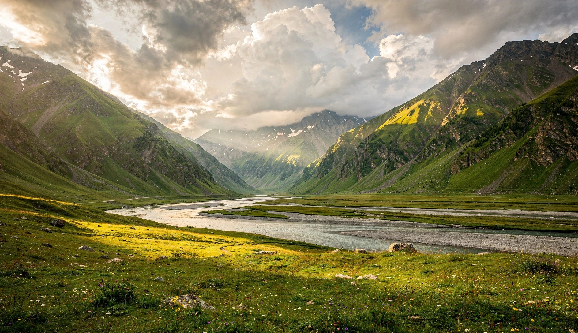 Panoramic view of Truso Valley with the Terek River winding through green alpine meadows beneath dramatic Caucasus mountain peaks